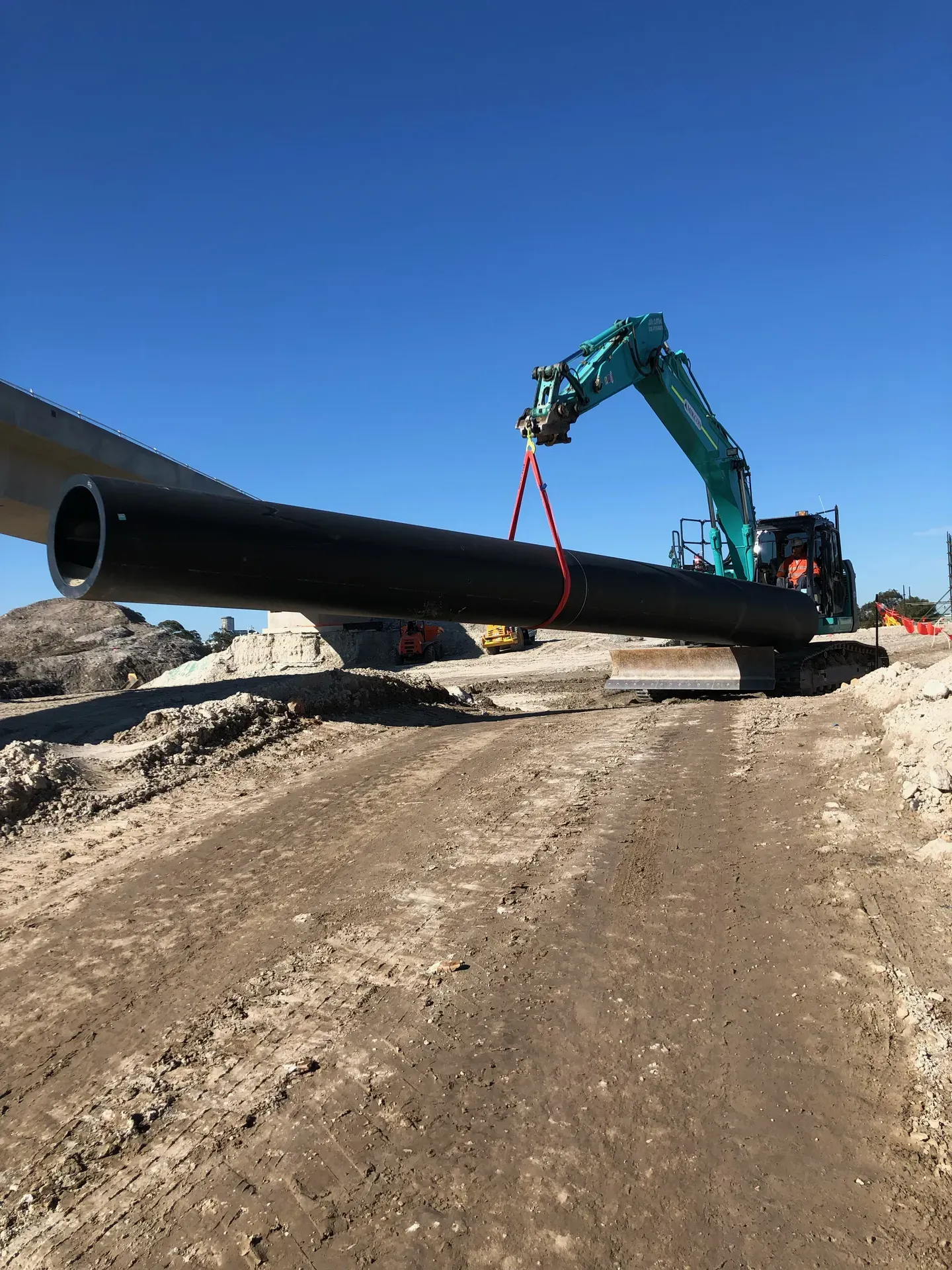 Currey Group excavator lifting a large HDPE pipeline on site